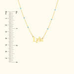 Gold necklace featuring the name "Lyla" with blue accents and a ruler for scale.