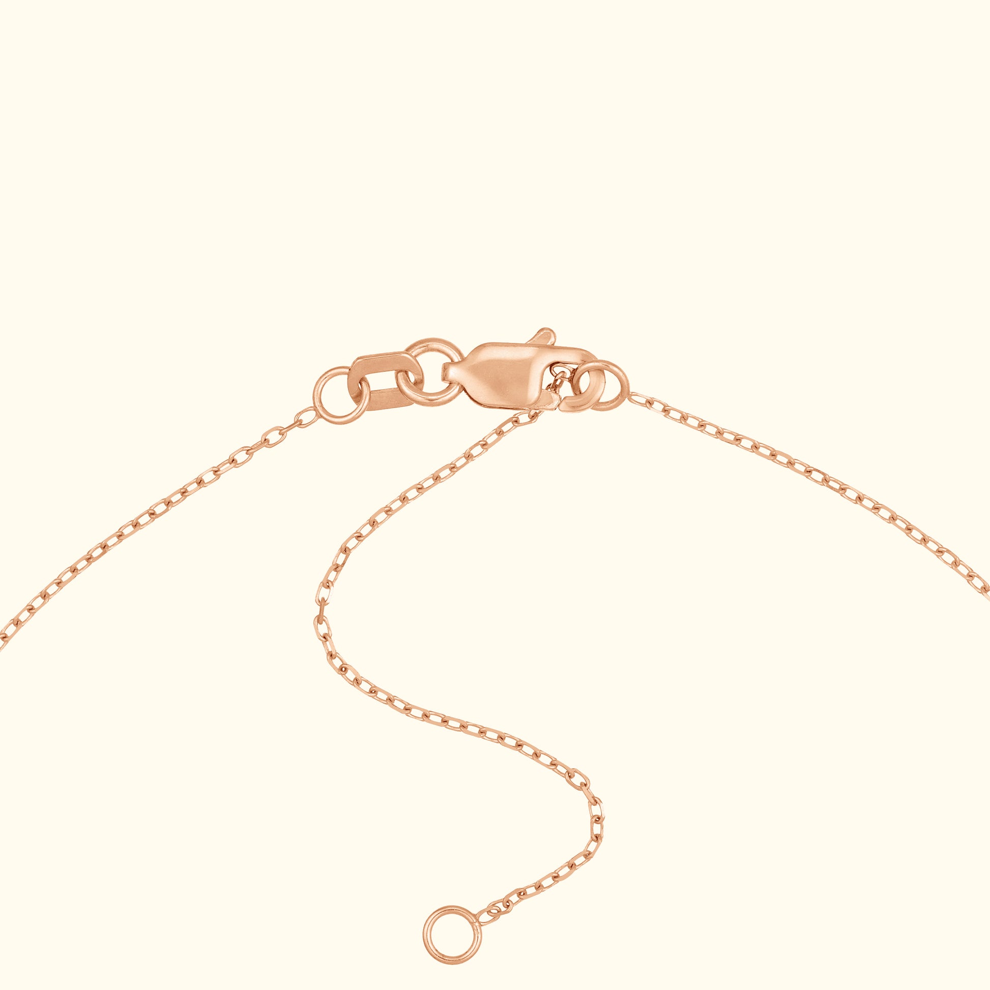 Rose gold necklace clasp with chain detail against a light background.