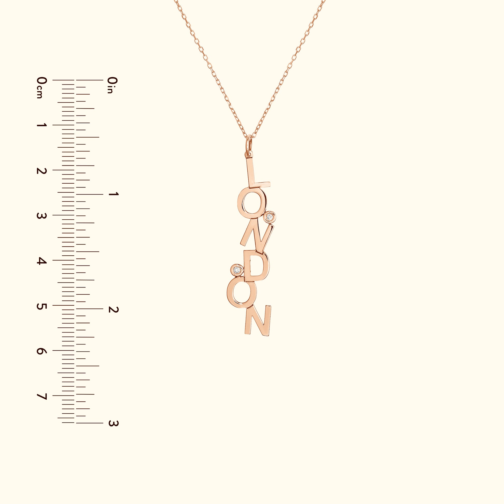 Rose gold pendant necklace with the word "LONDON" and small embellishments.