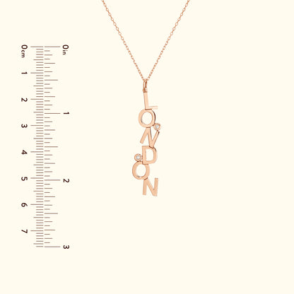 Rose gold pendant necklace with the word "LONDON" and small embellishments.