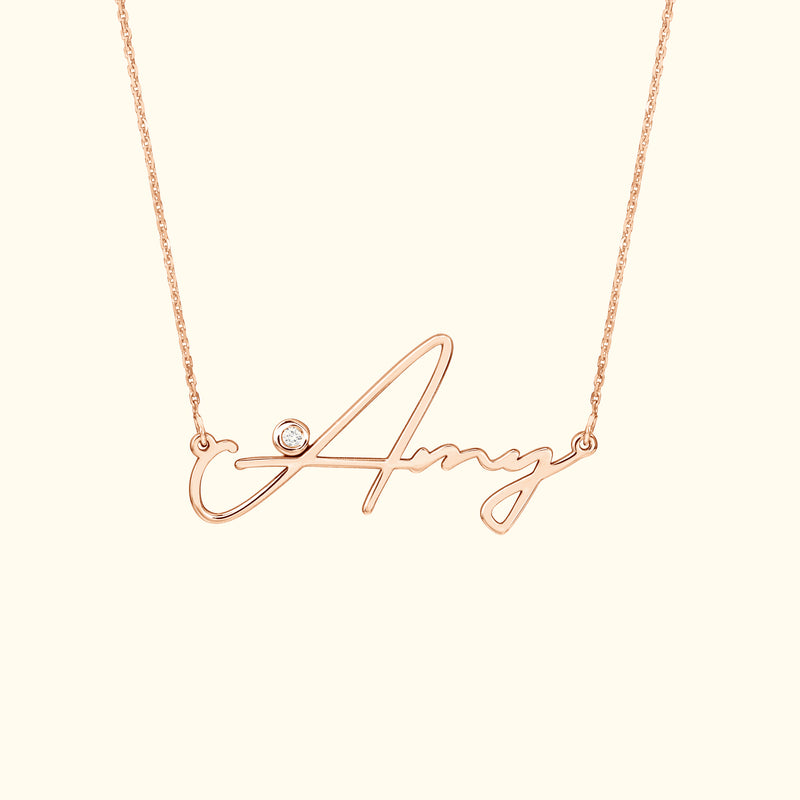 Rose gold necklace featuring a cursive name "Amy" with a small diamond accent.