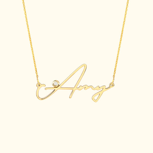 Gold necklace featuring a cursive name "Amy" with a small diamond accent.