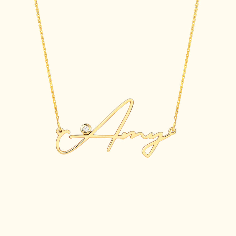 Gold necklace featuring a cursive name "Amy" with a small diamond accent.