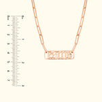 Rose gold chain necklace with a rectangular nameplate and decorative font.