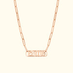 Rose gold chain necklace with a rectangular pendant featuring engraved lettering and a diamond accent.