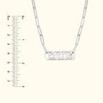 Silver necklace with a rectangular pendant displaying a stylized inscription.