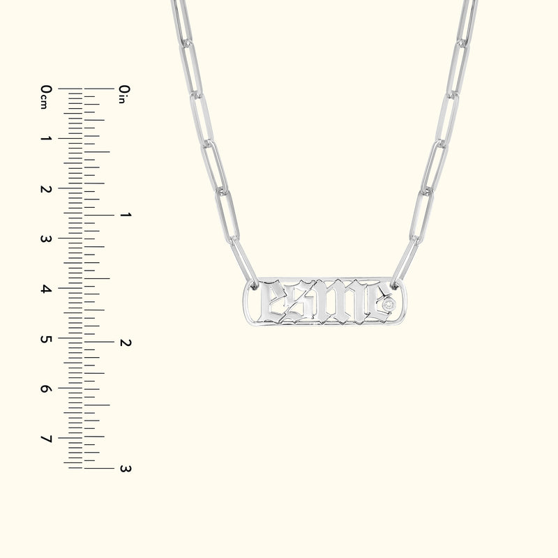 Silver necklace with a rectangular pendant displaying a stylized inscription.