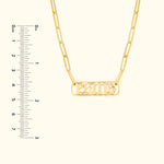 Gold necklace with a chain and a rectangular pendant featuring engraved letters.
