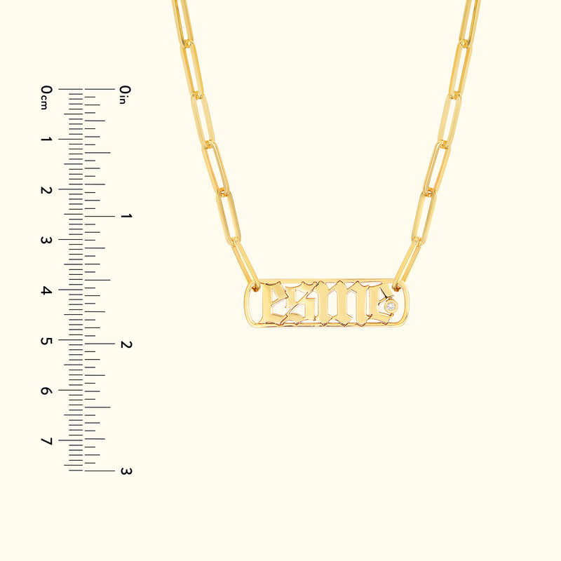 Gold necklace with a chain and a rectangular pendant featuring engraved letters.
