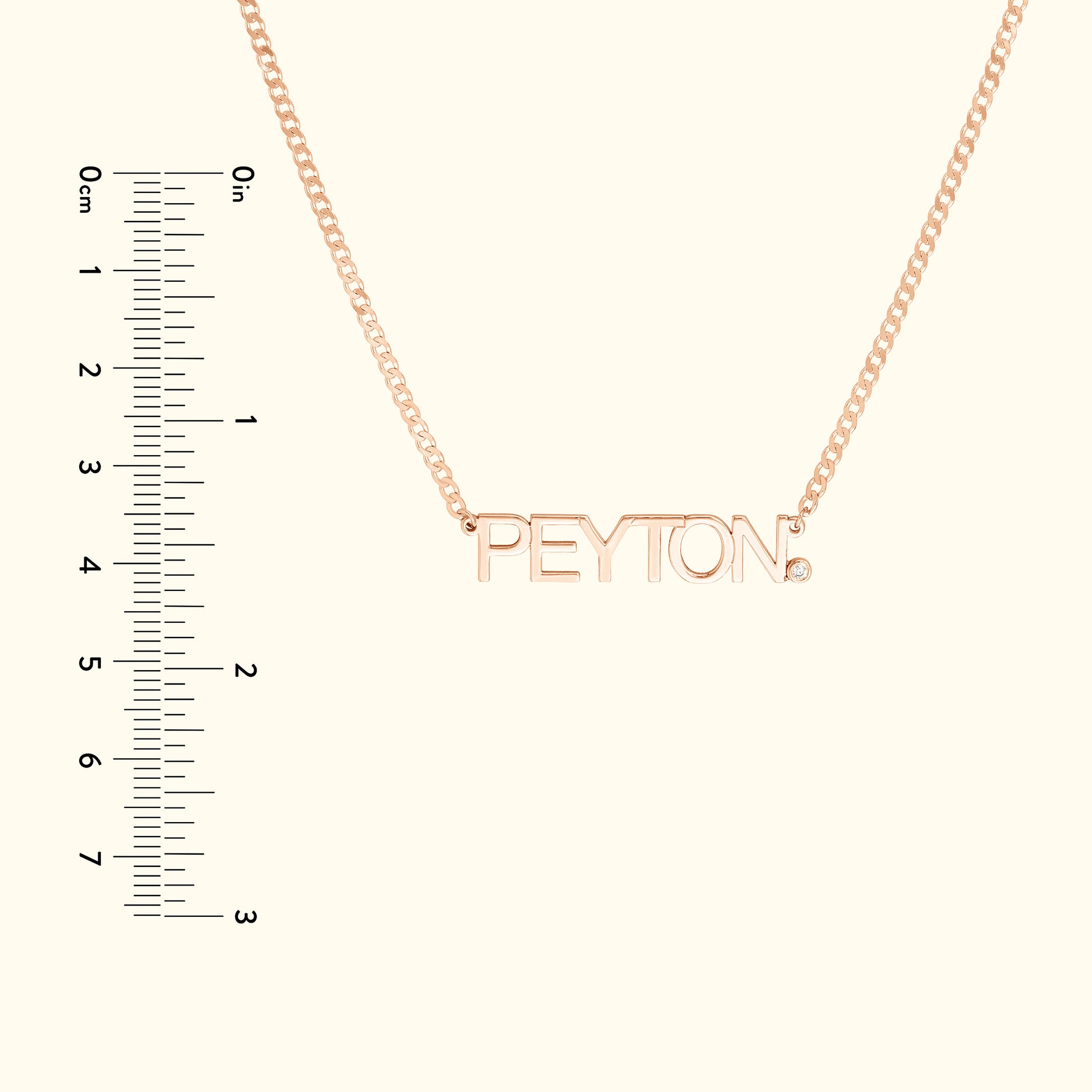 Rose gold necklace with the name "PEYTON" and a small diamond accent. Ruler for scale.