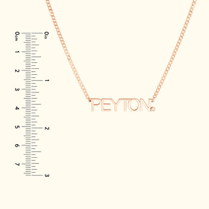 Rose gold necklace with the name "PEYTON" and a small diamond accent. Ruler for scale.