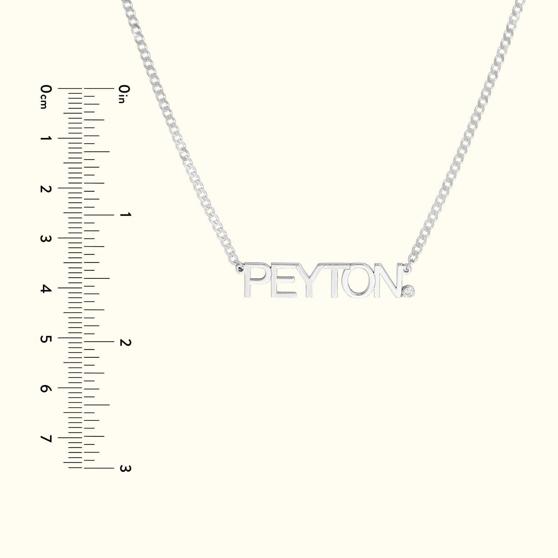 Silver necklace with a nameplate reading "PEYTON," alongside a ruler for scale.