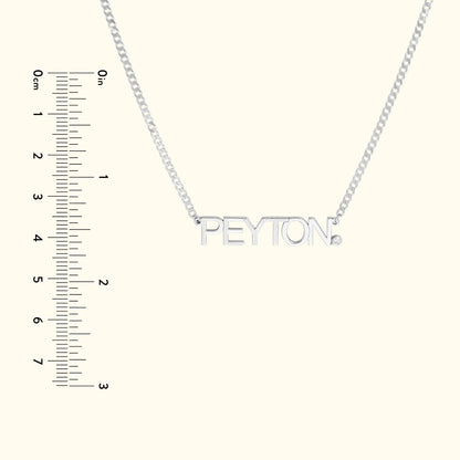 Silver necklace with a nameplate reading "PEYTON," alongside a ruler for scale.