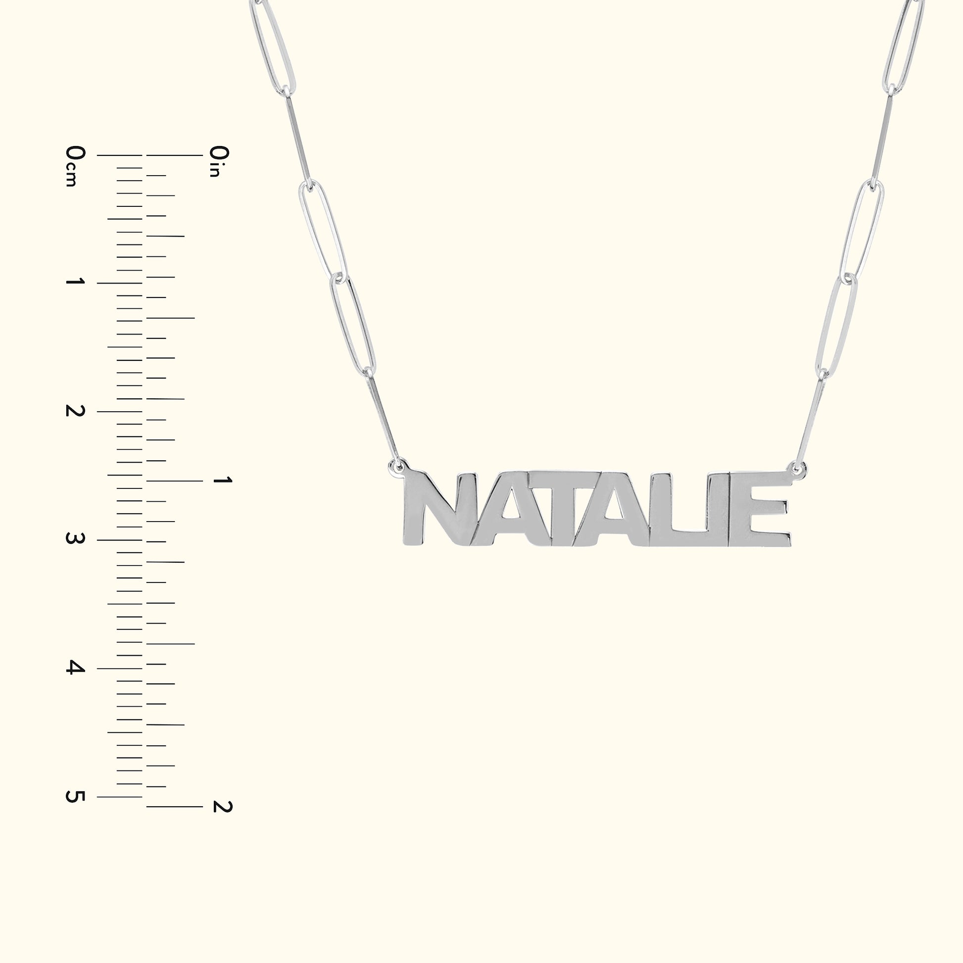 Silver name necklace with the word "NATALIE" on a chain, next to a ruler for scale.