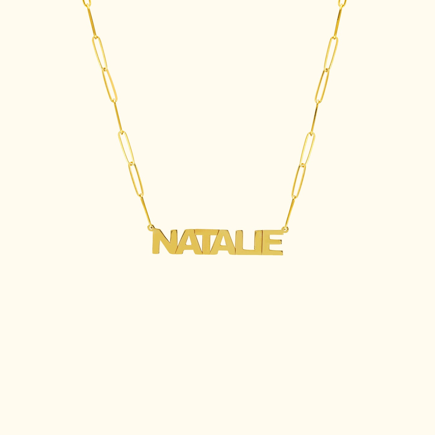 Gold name necklace with the word "NATALIE" in a bold font on a linked chain.