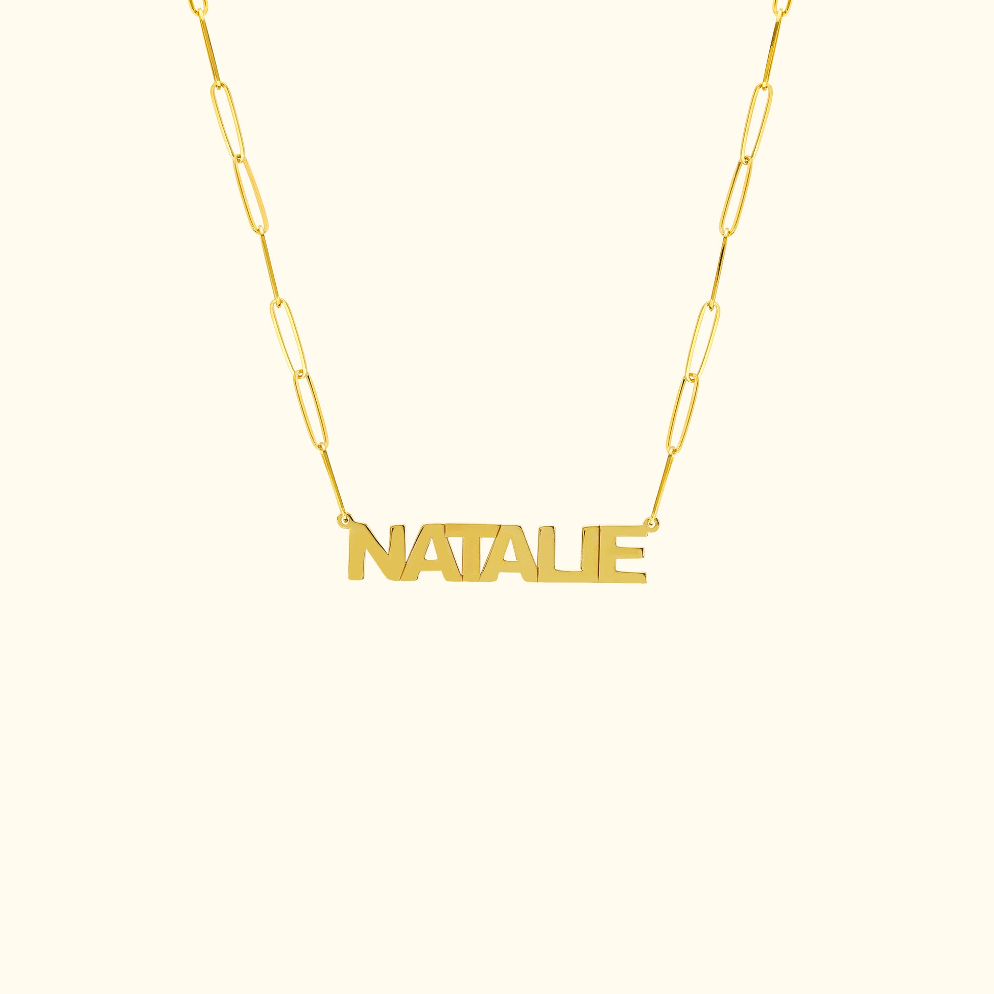 Gold name necklace with the word "NATALIE" in a bold font on a linked chain.