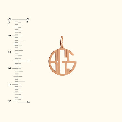 Rose gold monogram pendant with an open design, accompanied by a ruler for size reference.