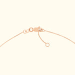 Close-up of a rose gold necklace clasp with delicate chain links.