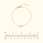 Delicate rose gold bracelet with a geometric charm, displayed with a ruler for size reference.