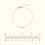 Silver chain bracelet with a geometric charm, placed against a neutral background.