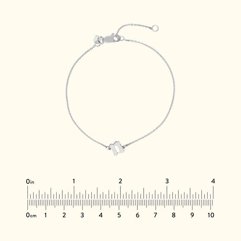 Silver chain bracelet with a geometric charm, placed against a neutral background.