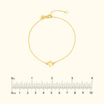 Golden bracelet with a minimalist design and a clasp, displayed with a ruler for scale.