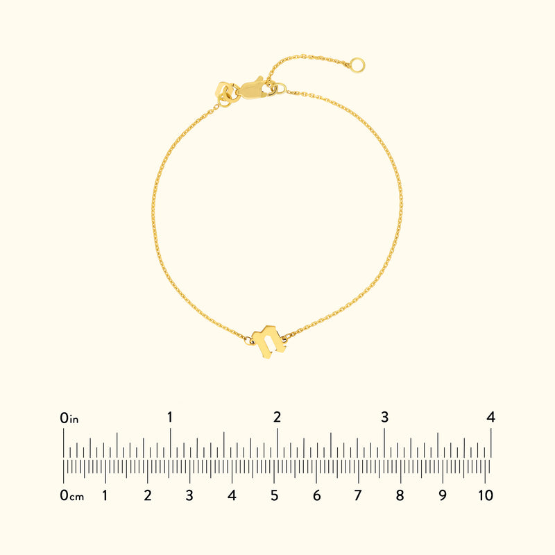 Golden bracelet with a minimalist design and a clasp, displayed with a ruler for scale.