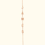 Rose gold necklace with letters spelling "JAMES" hanging from a delicate chain.