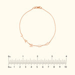 Rose gold bracelet with letters spelling "J A N I S" attached to a delicate chain.