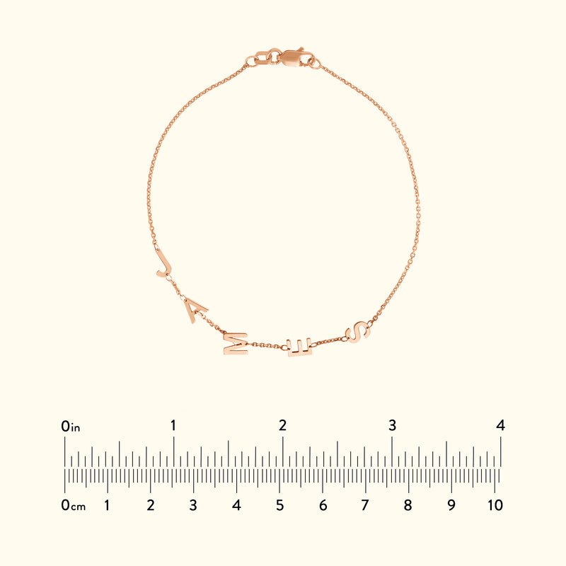 Rose gold bracelet with letters spelling "J A N I S" attached to a delicate chain.