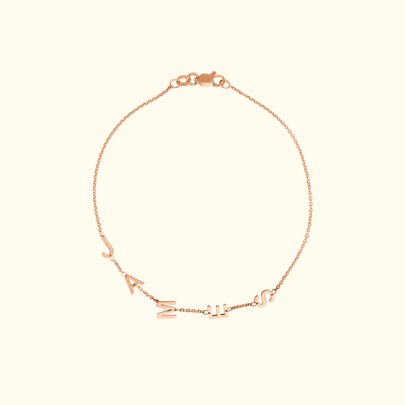 Delicate rose gold bracelet with hanging letter charms.