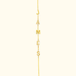 Gold necklace with letters spelling "JAMES" hanging from a delicate chain.