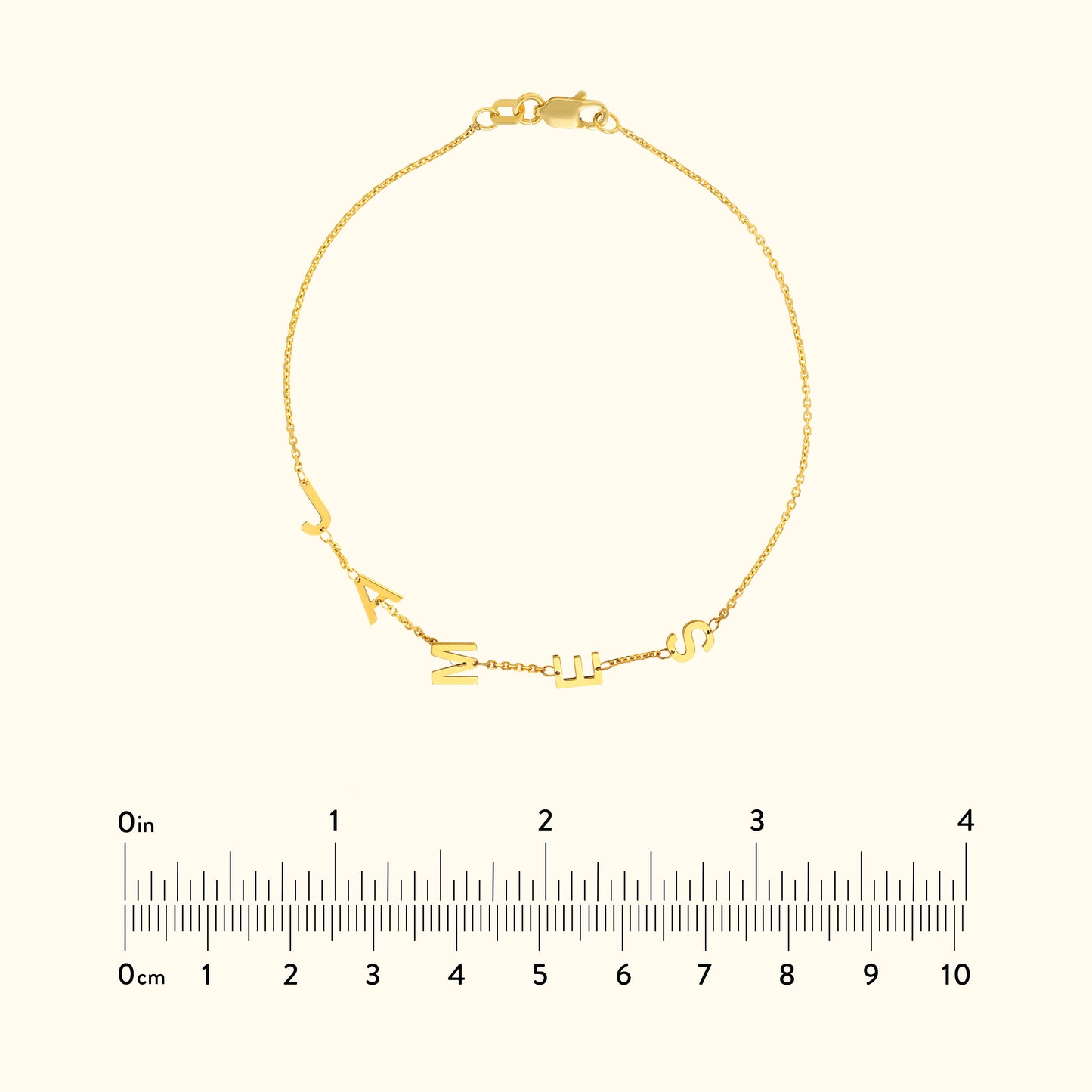 Gold bracelet featuring alphabet charms, displayed with a ruler for size reference.