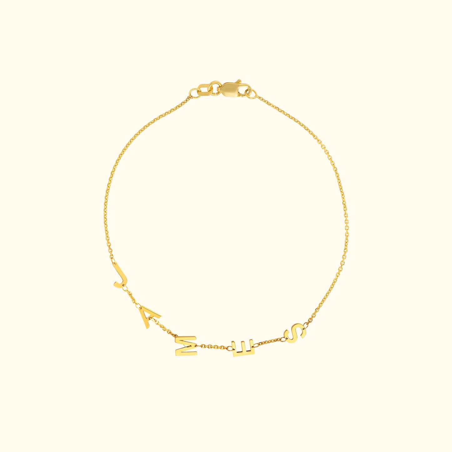 Golden bracelet with hanging letters forming a name or word, elegant design on a light background.