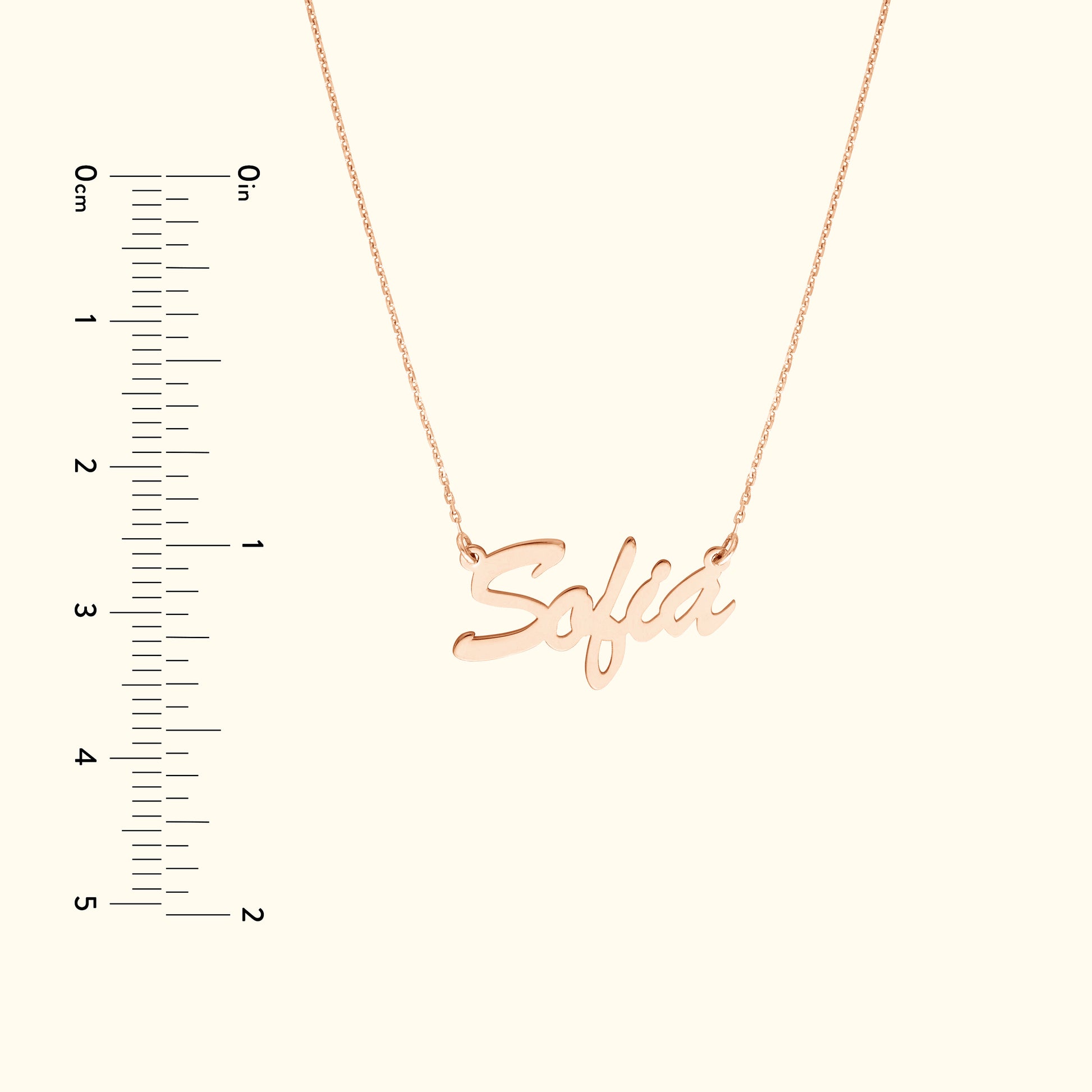 Rose gold necklace with the name "Sofia" in cursive, alongside a ruler for size reference.