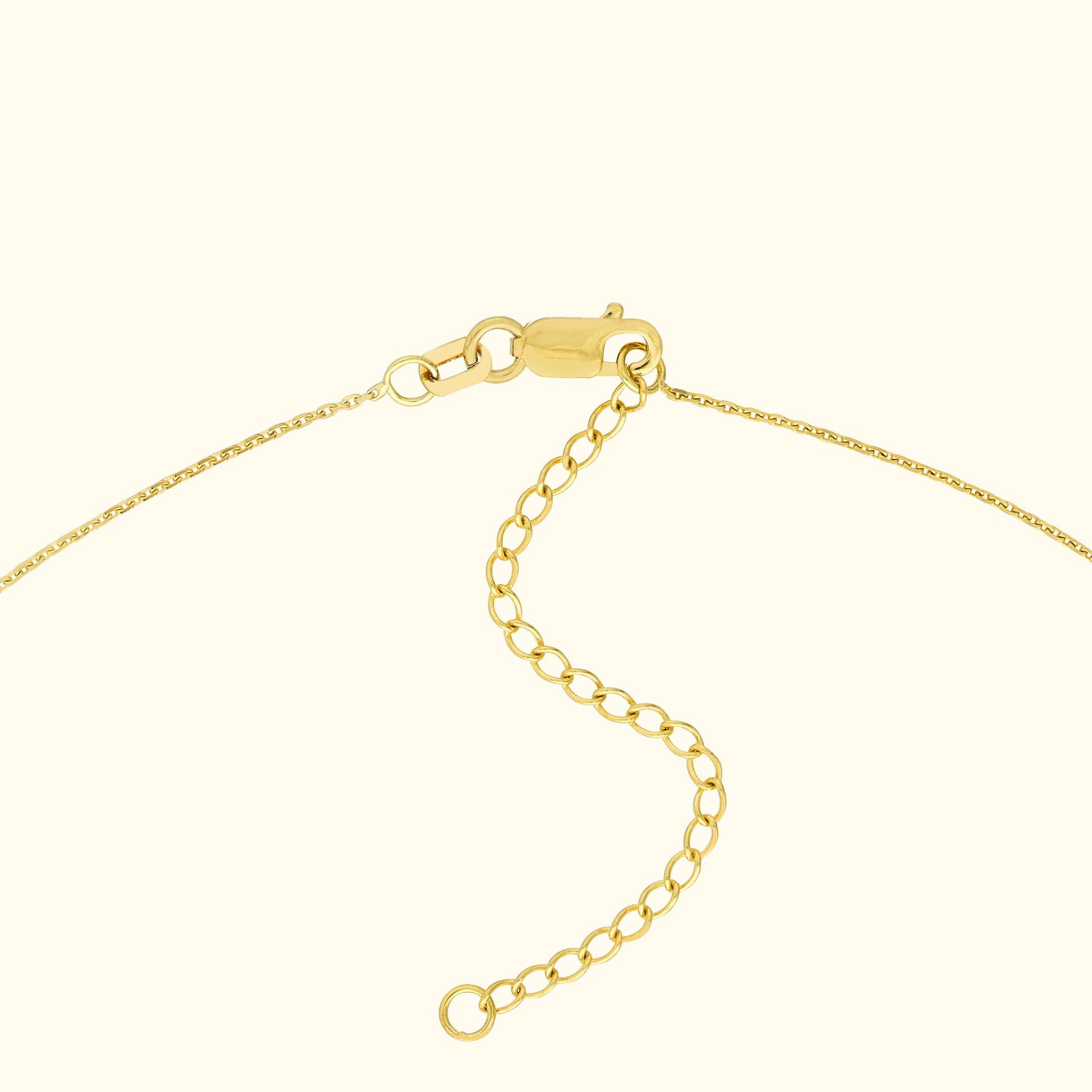 Close-up of a gold chain necklace clasp with an adjustable extension.