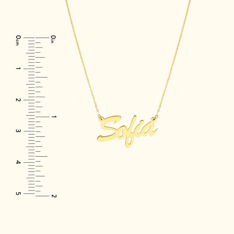 Gold necklace featuring the name "Sofia" in a cursive font, with a ruler for scale.