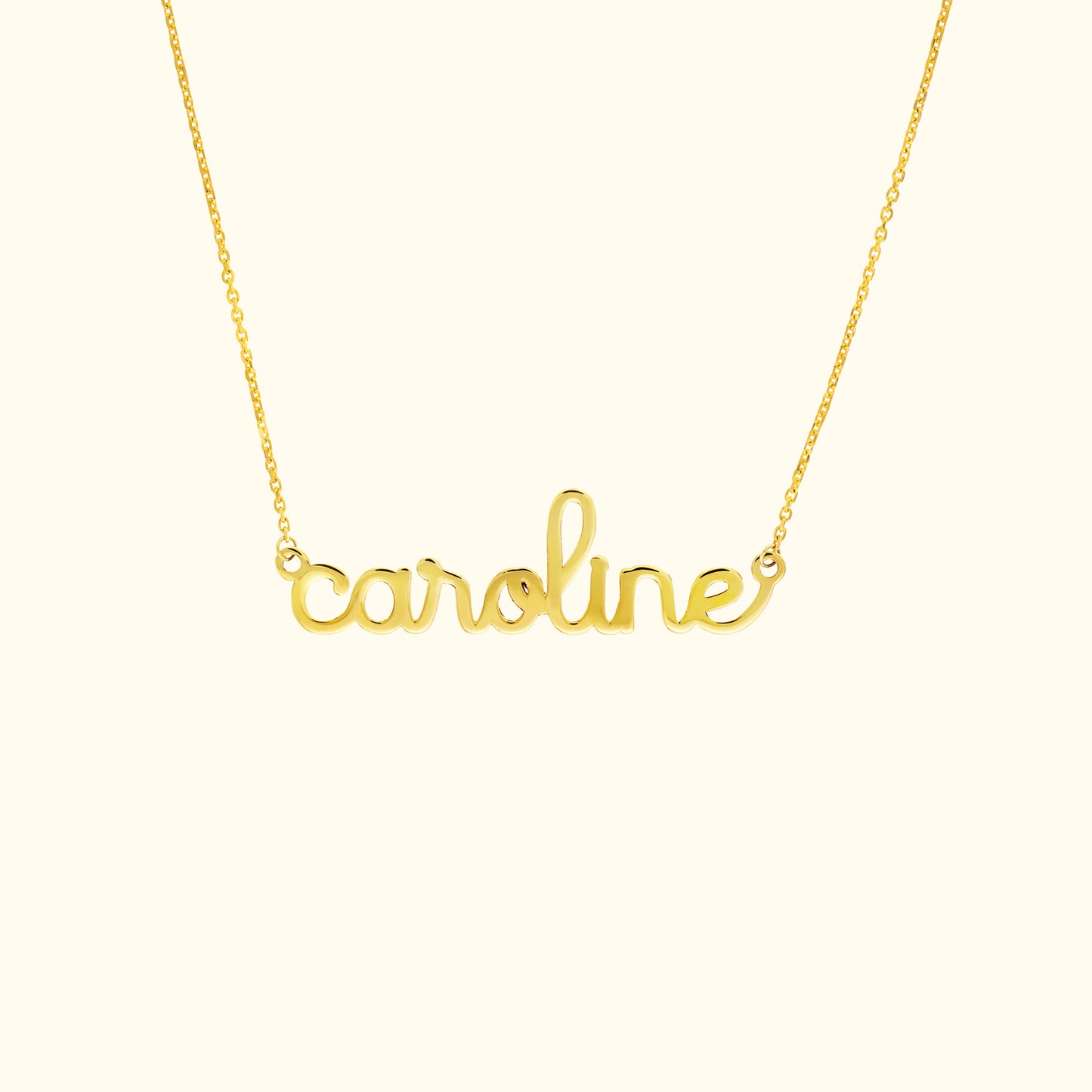 Gold name necklace featuring the word "caroline" in a cursive font.