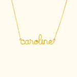 Gold name necklace featuring the word "caroline" in a cursive font.