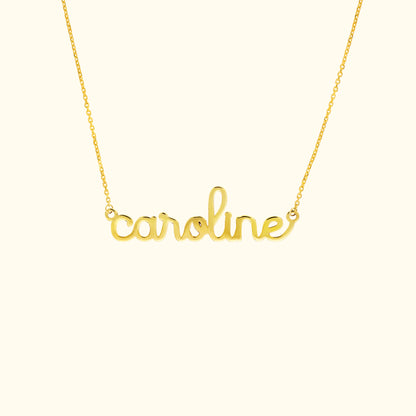 Gold name necklace featuring the word "caroline" in a cursive font.