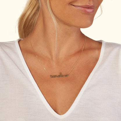 Gold necklace with the word "Caroline" in cursive, worn by a woman.