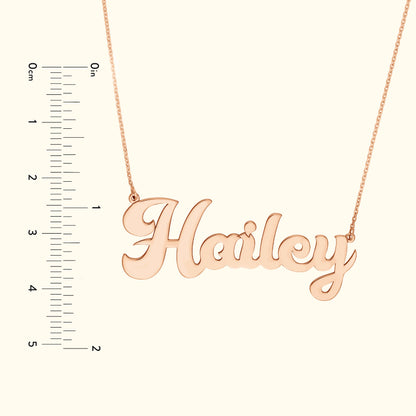 Rose gold name necklace reading "Hailey," alongside a ruler for size reference.