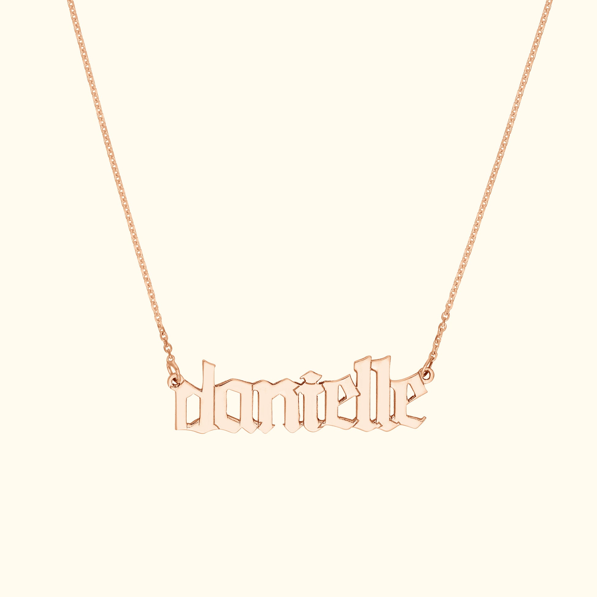 Rose gold name necklace featuring the name "danielle" in ornate lettering.