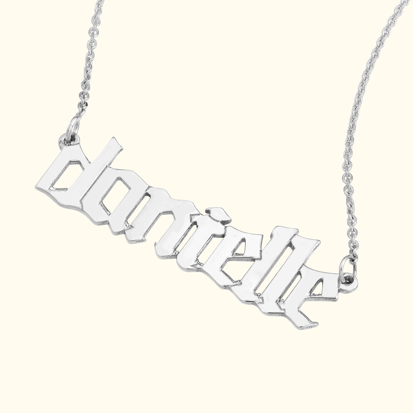 Silver name necklace with the text "danielle" in a stylized font.