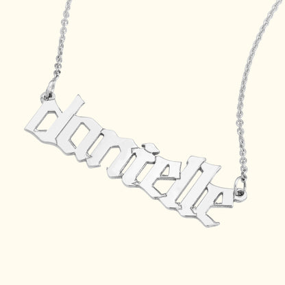 Silver name necklace with the text "danielle" in a stylized font.