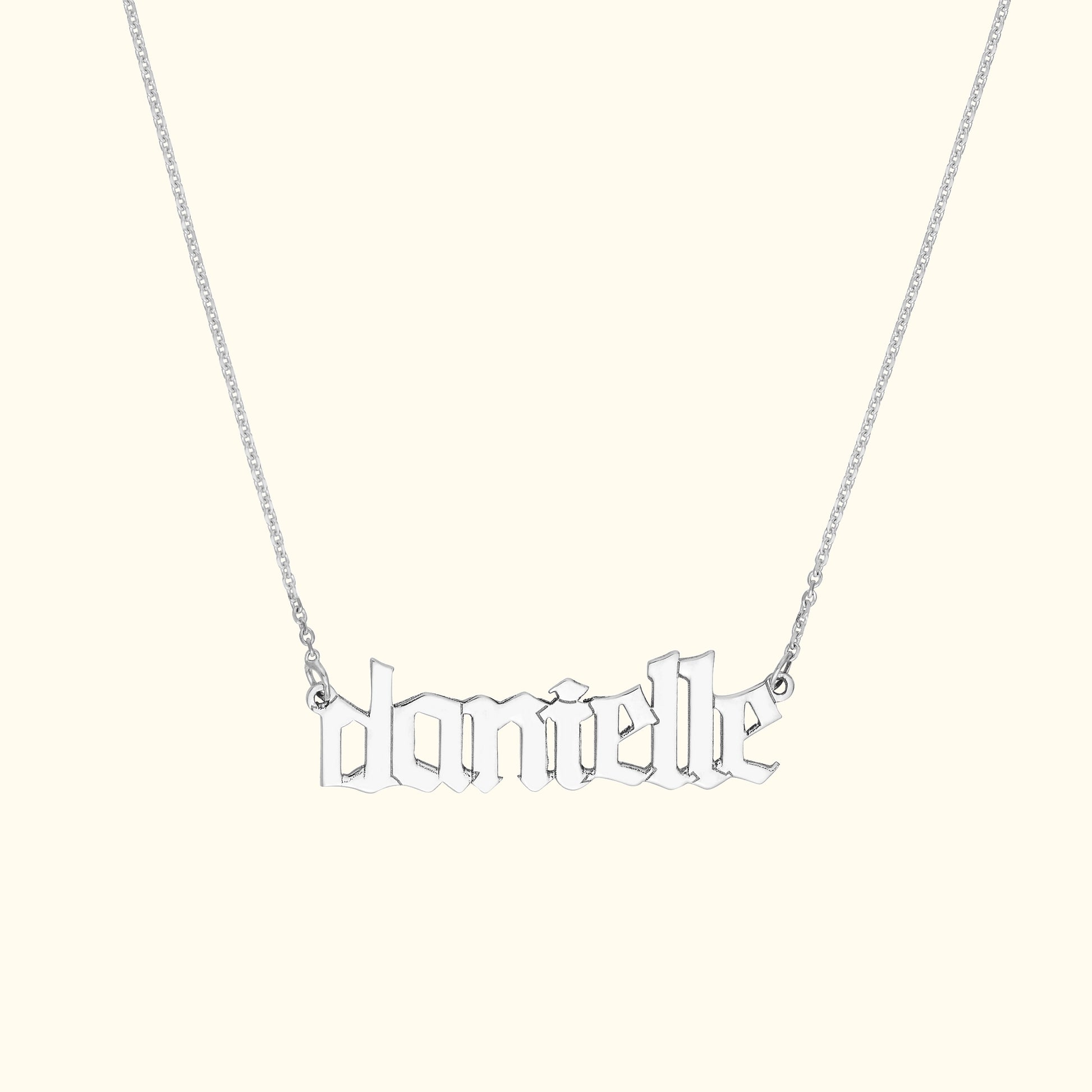 Silver name necklace spelling "danielle" in decorative font, hanging on a delicate chain.