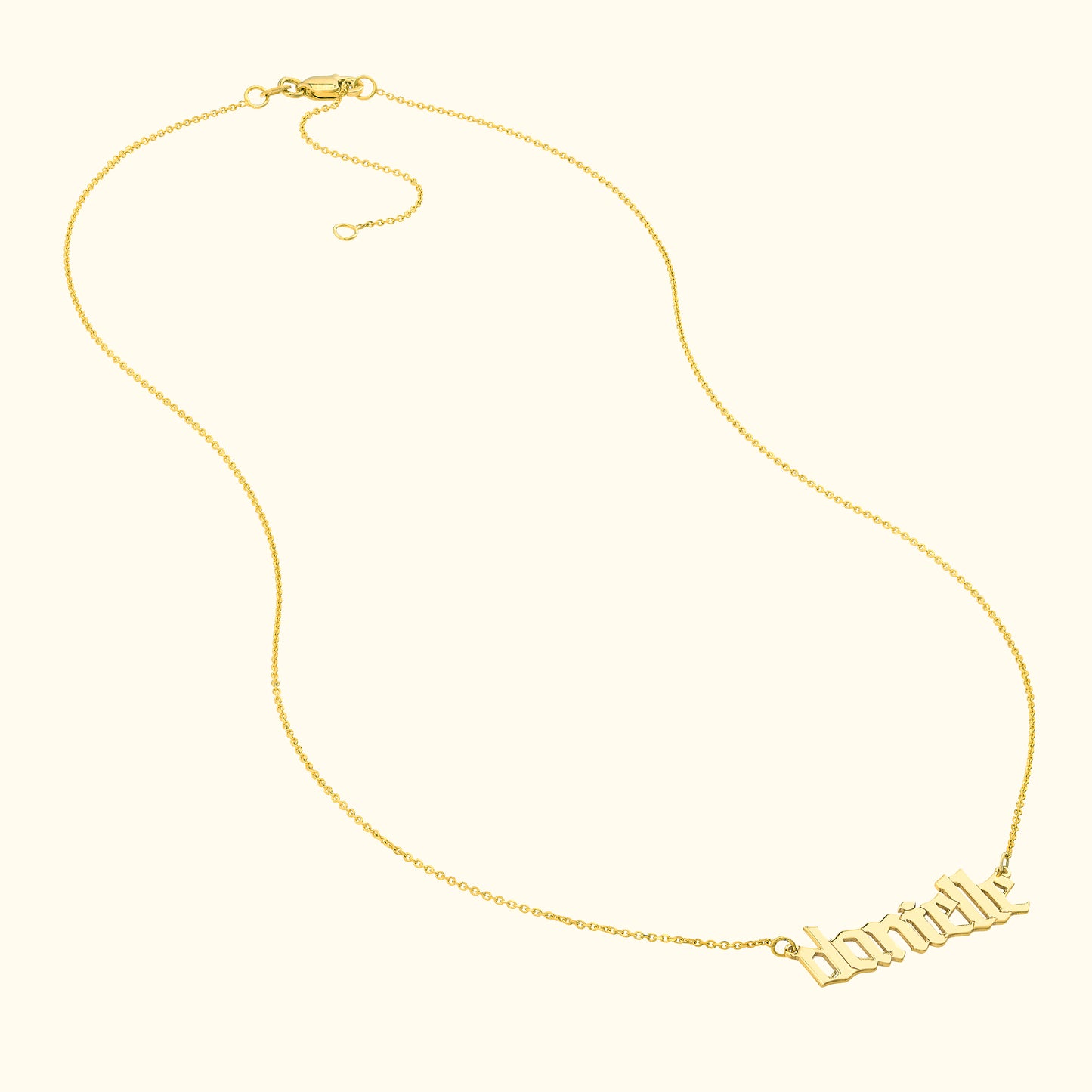 Gold name necklace with a cursive font, resting against a light background.