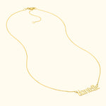 Gold name necklace with a cursive font, resting against a light background.