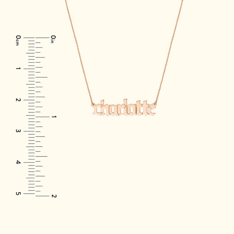 Rose gold name necklace with the word "charlotte," alongside a measurement scale.