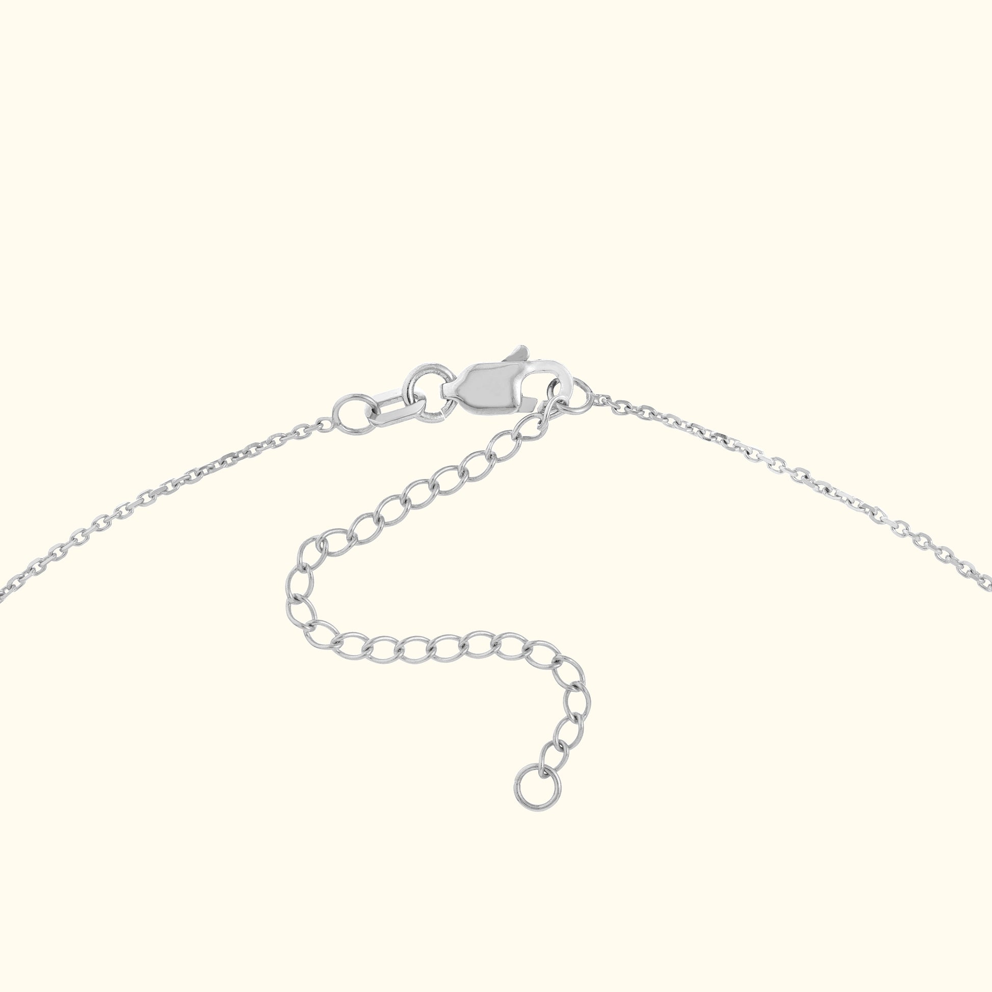 Close-up of a silver necklace clasp and adjustable chain links.